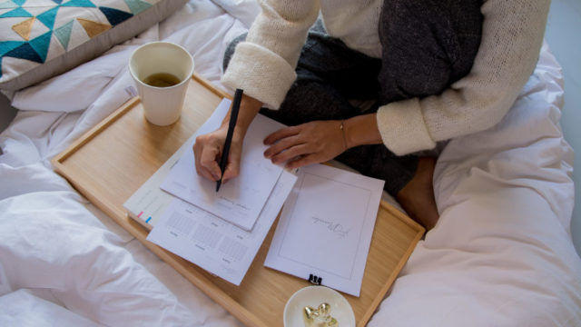 Woman writing or studying on a table in bed, with coffee preparing to find a co-op job in Canada. Photo credit @paicooficial