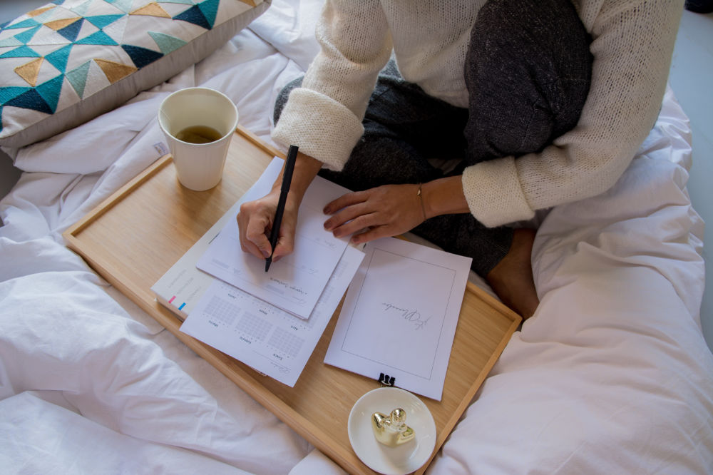 Woman preparing to find a job in Canada, writing notes on a table on her bed - photo credit @paicooficial