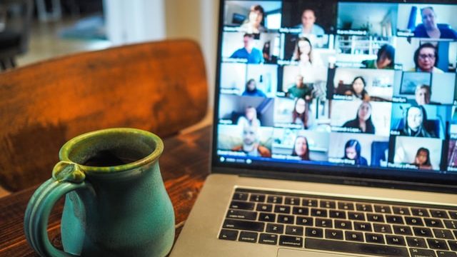 coffee cup and laptop showing online meeting - group of people virtual networking